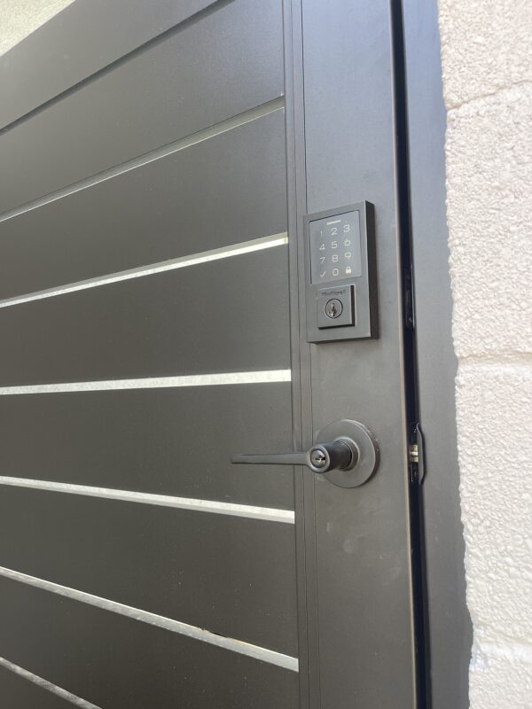 Close-up of a black aluminum gate with keypad and handle, showcasing modern design.