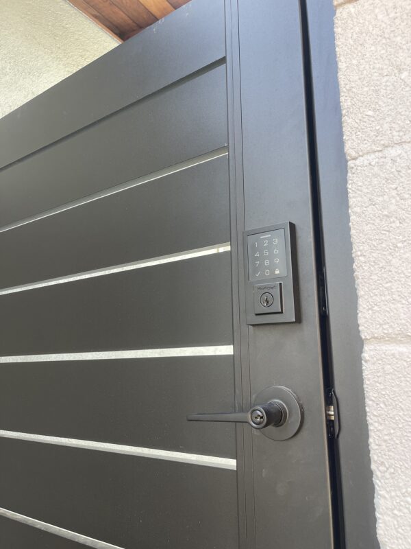 Close-up of a modern black aluminum gate with a keypad lock and sleek design.
