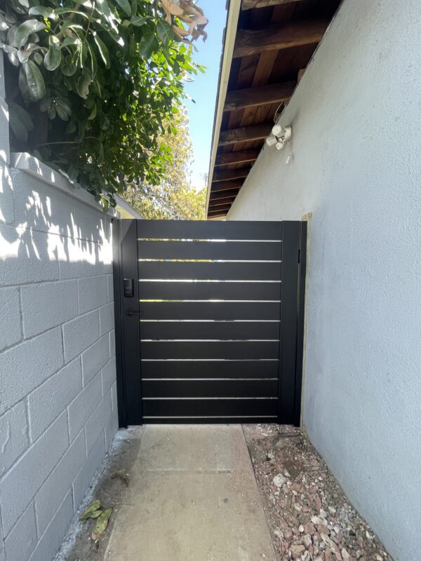 A modern black aluminum gate installed between two walls, enhancing the outdoor space.
