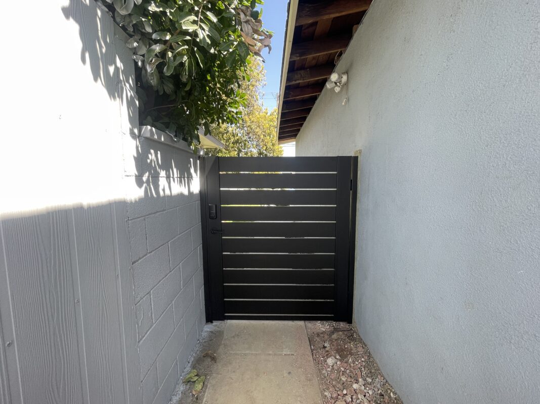 A modern black aluminum side gate against a gray wall, enhancing privacy and style.
