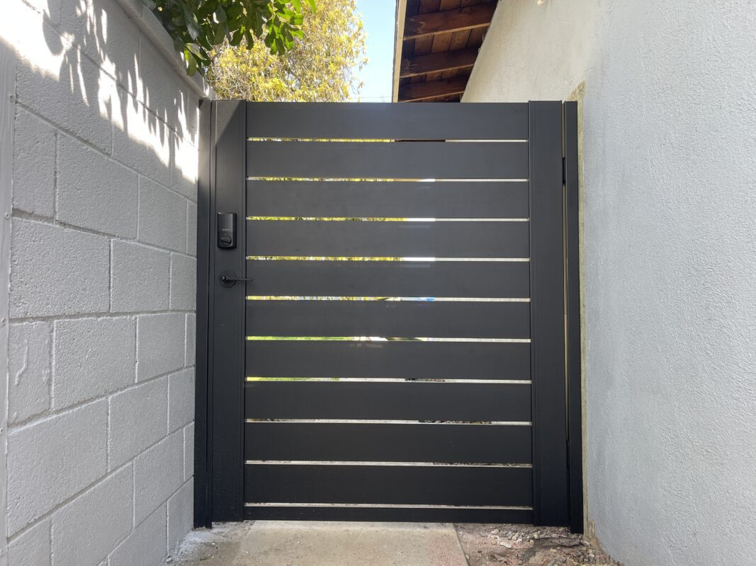 Modern black aluminum side gate installed beside a wall, enhancing privacy and style.