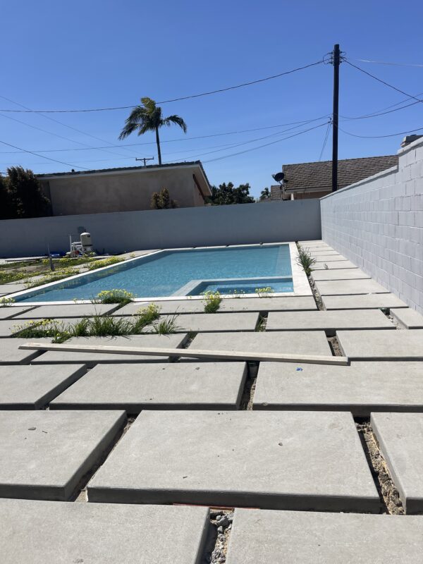 A newly installed fence around a pool area with decorative concrete slabs and greenery.