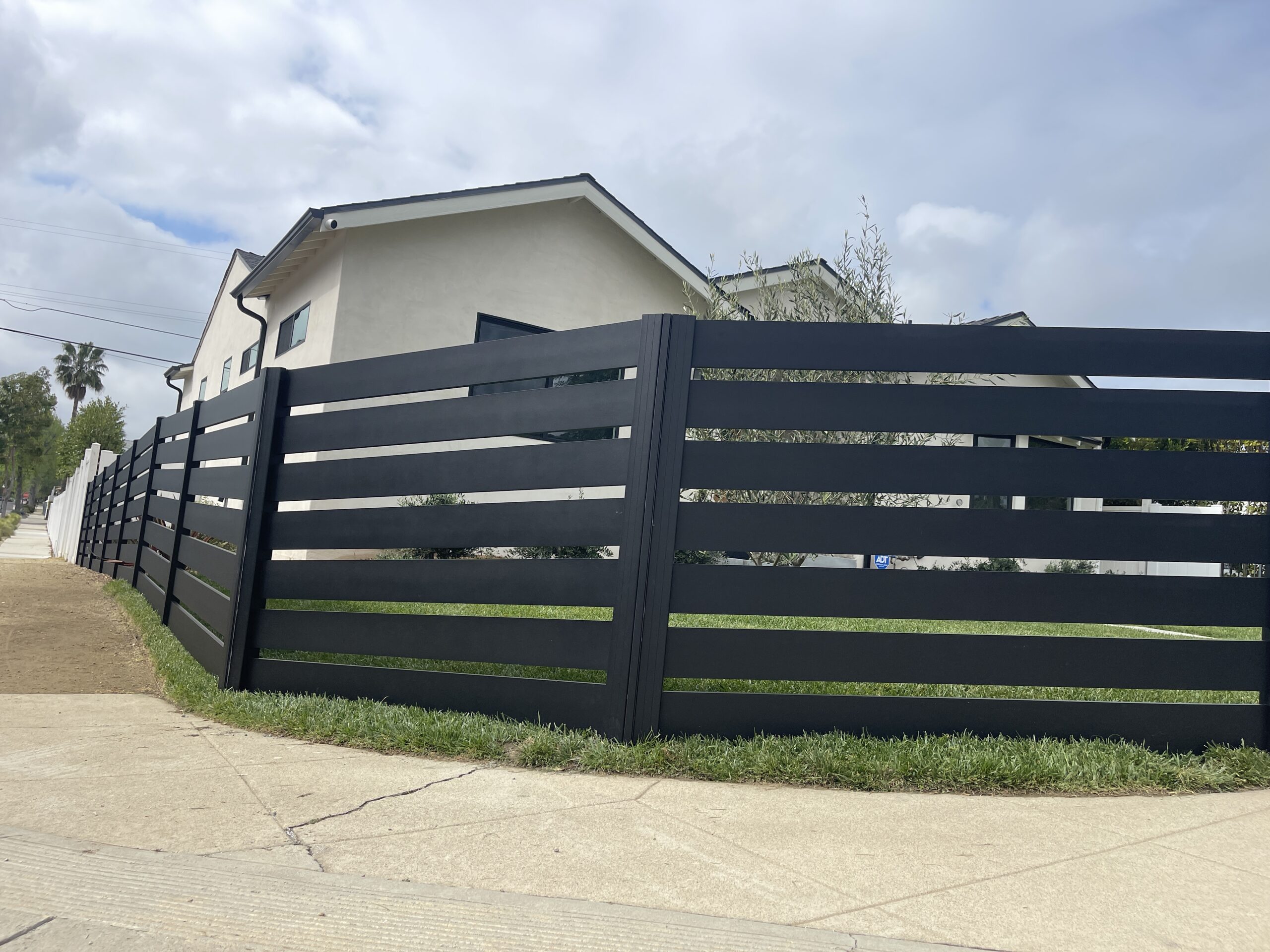 Modern black aluminum fence enhances aesthetics and security for a property.