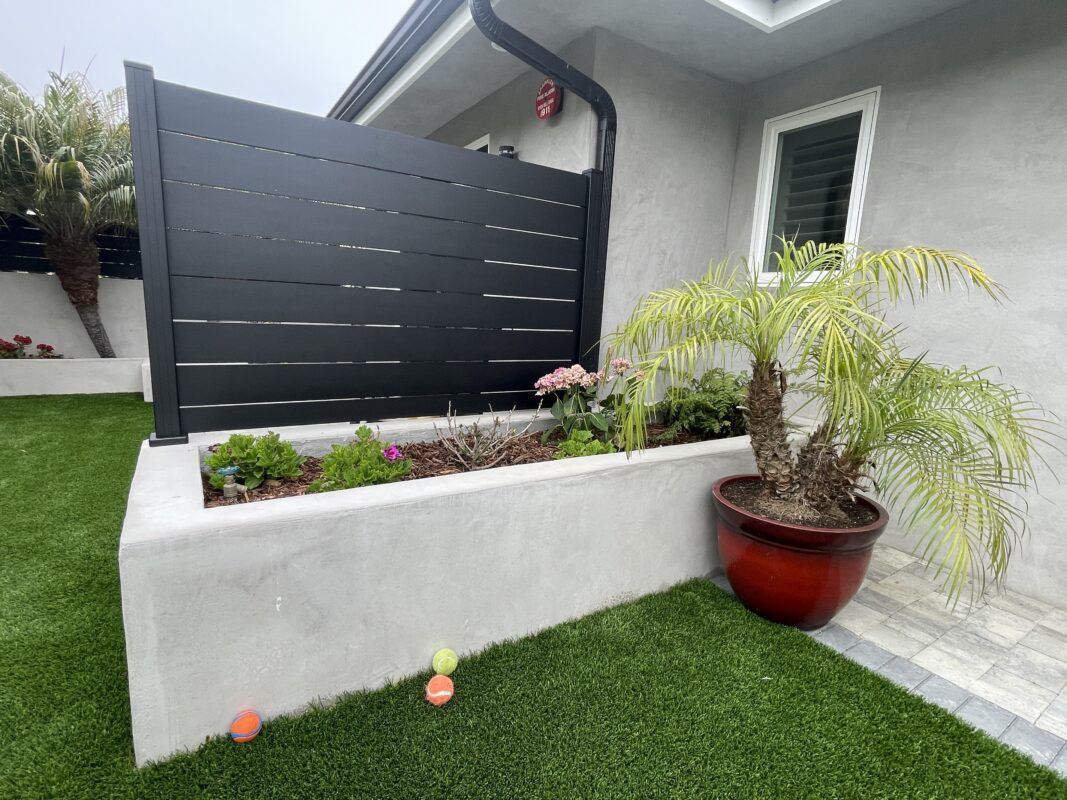 Modern black wall topper alongside vibrant landscaping in a landscaped outdoor space.
