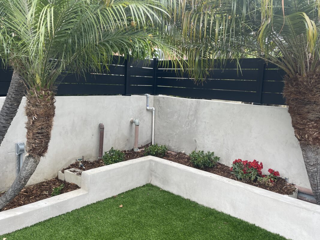 Modern black fence with palms and flowers, enhancing a contemporary outdoor space.