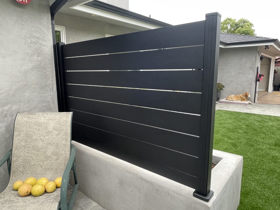 Modern black wall topper installed in a Ventura backyard, with lounge chair and yard.