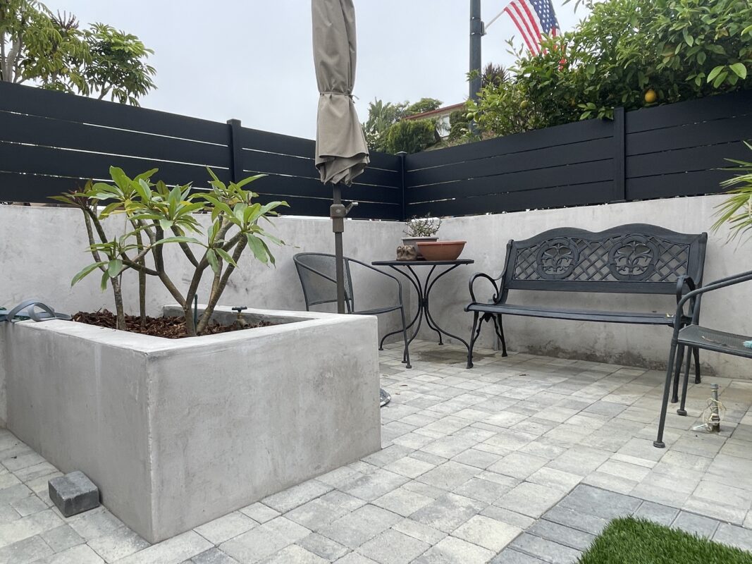 Modern black fence and concrete patio enhance outdoor space with elegance and privacy.