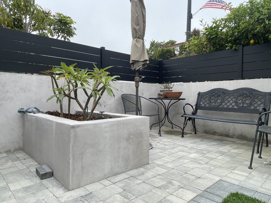 Modern black fence with a planter and seating area in a coastal patio setting.