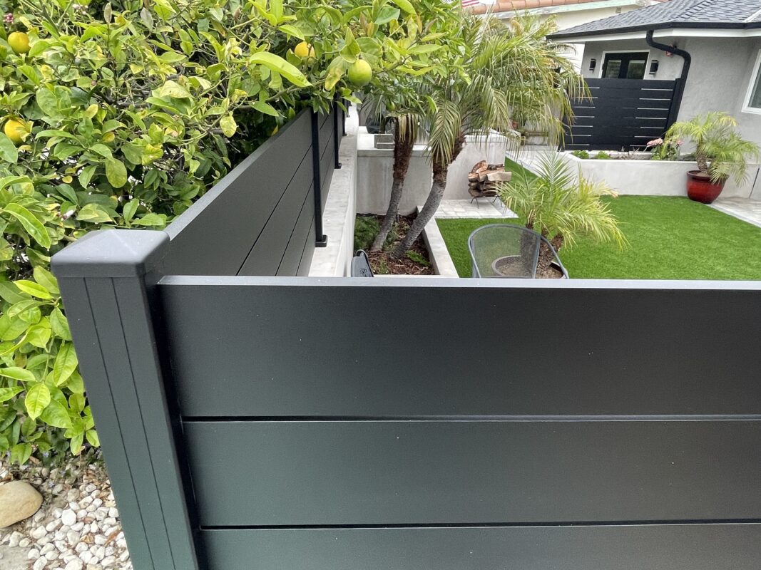 Modern black wall topper and privacy fence enhancing a coastal garden space.