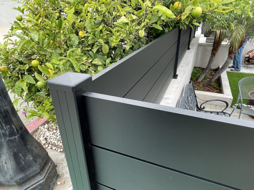 Modern black wall topper adds elegance to a lush green landscape in Ventura, CA.