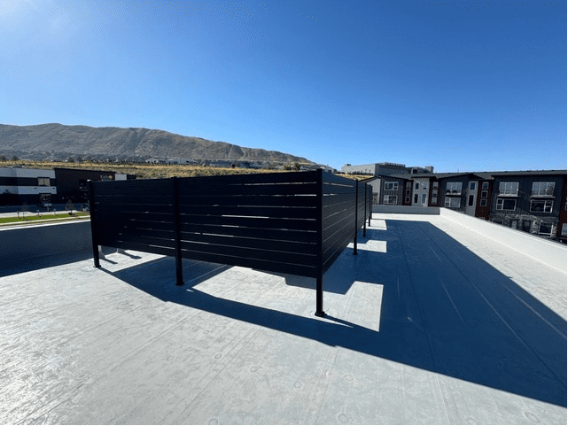 Black aluminum fence installed on a rooftop with mountain backdrop in Lehi, UT.
