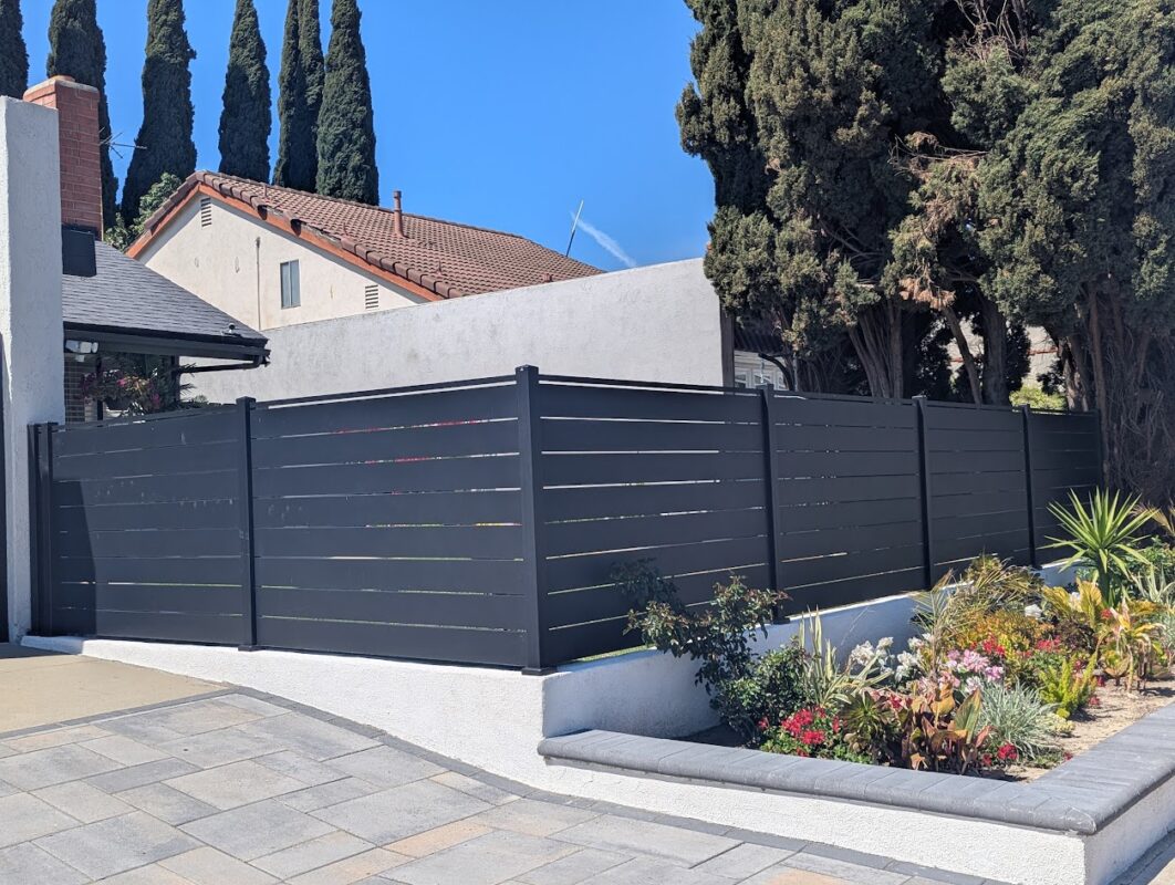 Modern black aluminum fence surrounding a landscaped garden in a residential area.