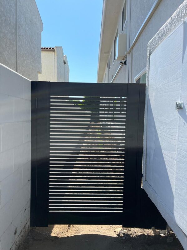 A modern black aluminum gate installed between two buildings in Torrance, CA.