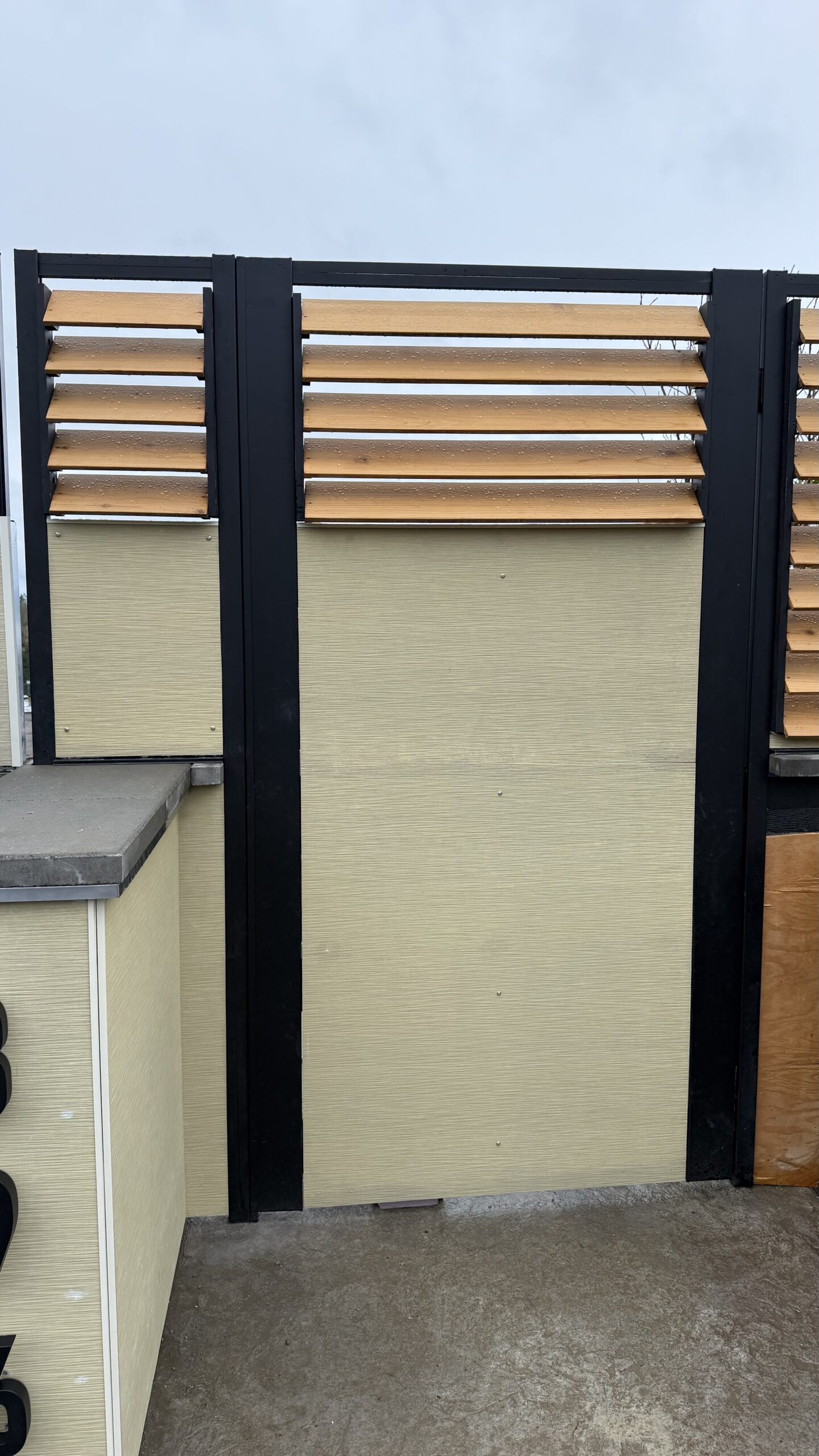 A modern fence with wood slats and black borders installed at a residential property.
