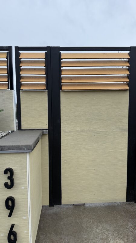Modern fence installation showing a sleek driveway gate with wood accents.