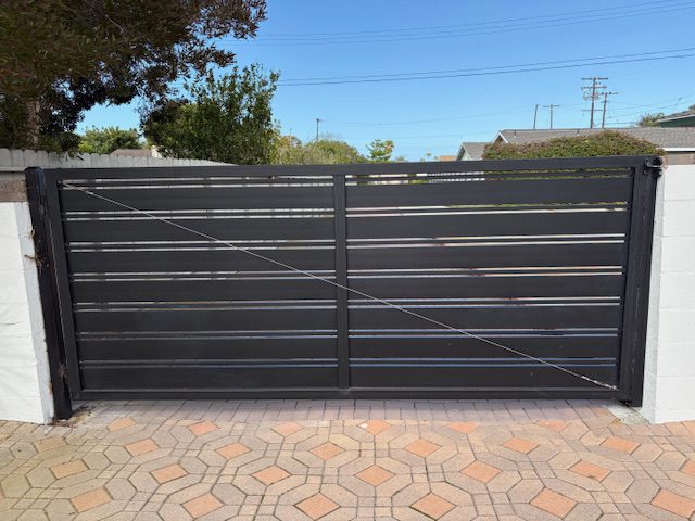 Black aluminum driveway gate installed in a stylish outdoor setting.